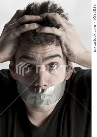 Man with mouth covered by masking tape preventing speech.. Man with mouth covered by masking tape preventing speech.. 9556838