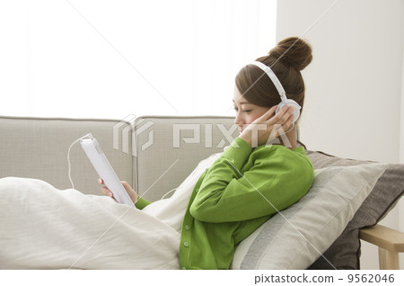 A young woman listening to music on a tablet A young woman listening to music on a tablet 9562046
