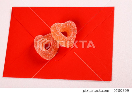 Two hearts from sugar candies on red envelope 9580899