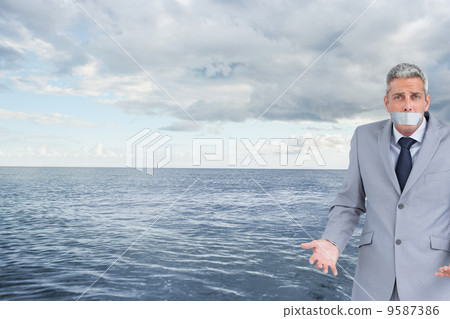 Composite image of businessman gagged with adhesive tape on mout Composite image of businessman gagged with adhesive tape on mout 9587386