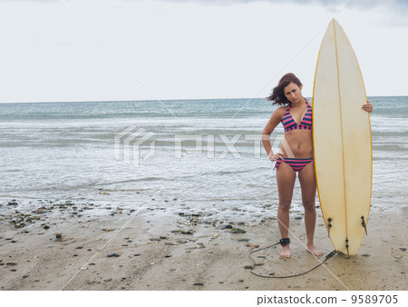 Full length of a bikini woman holding surfboard at beach Full length of a bikini woman holding surfboard at beach 9589705