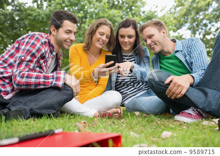Happy college students looking at mobile phone in park 9589715