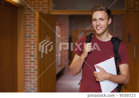 Handsome smiling student standing in hallway Handsome smiling student standing in hallway 9589725