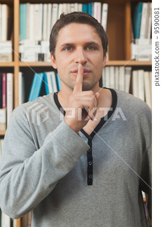 Male librarian making a sign to be quiet in library Male librarian making a sign to be quiet in library 9590081