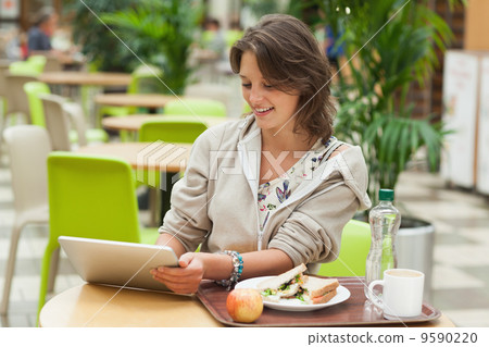 Woman using tablet PC in the cafeteria 9590220