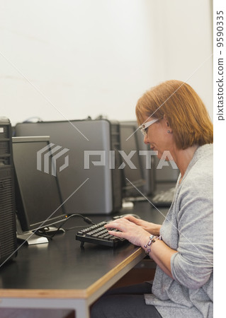 Focused mature student sitting in computer class 9590335