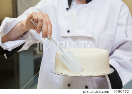 Chef finishing a cake with icing 9590472