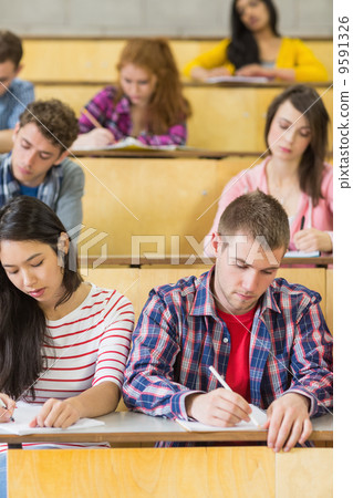 Students sitting at the lecture hall while writing 9591326