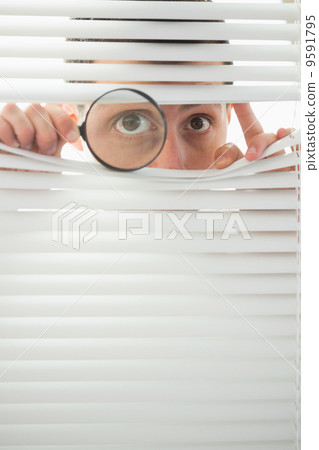 Male eyes spying through roller blind with magnifier Male eyes spying through roller blind with magnifier 9591795