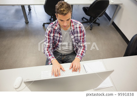 Handsome stern student working on computer 9591838