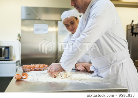 Serious head chef kneading dough 9591923