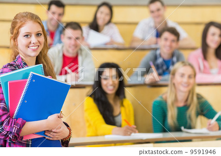 Smiling female with students sitting at the lecture hall