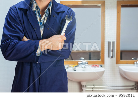 Plumber in blue boiler suit posing with wrench 9592011