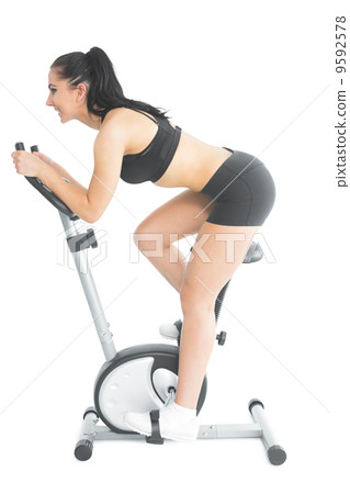 Profile view of sporty young woman training on an exercise bike 9592578