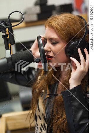 Concentrating beautiful singer recording a song 9592604