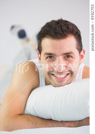 Cheerful handsome man lying in bed looking at camera 9592703