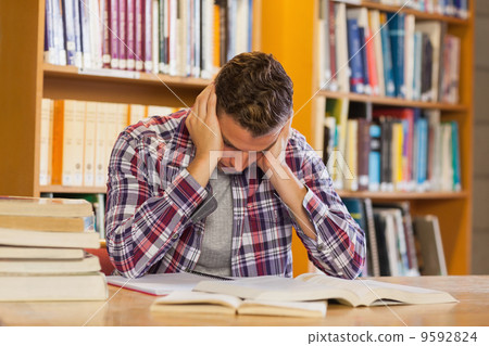 Handsome frustrated student studying his books Handsome frustrated student studying his books 9592824