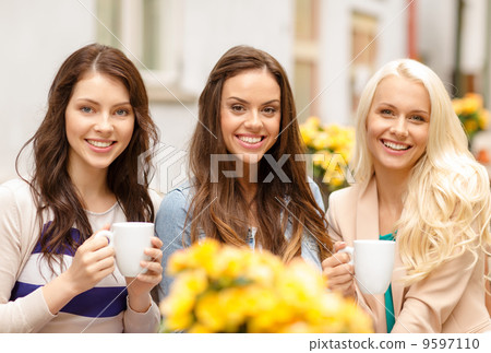 three beautiful girls drinking coffee in cafe three beautiful girls drinking coffee in cafe 9597110