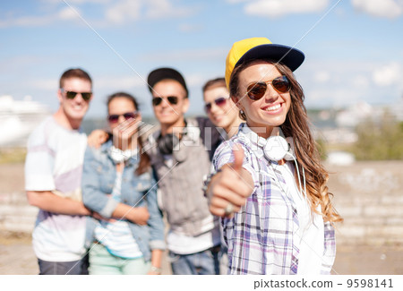 teenage girl with headphones and friends outside 9598141