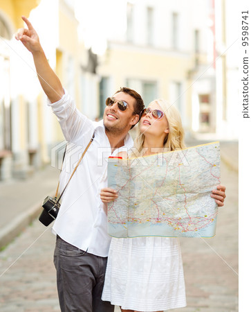 smiling couple in sunglasses with map in the city 9598741