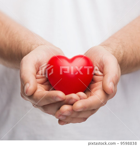 mans cupped hands showing red heart 9598838