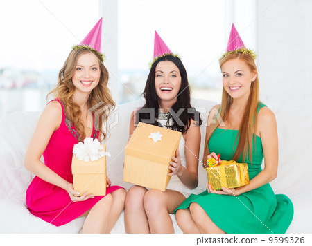 three smiling women in pink hats with gift boxes 9599326