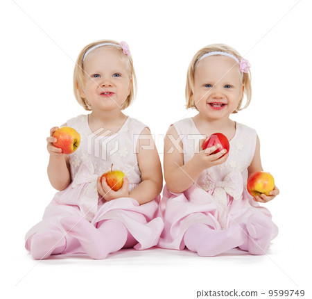 two identical twin girls playing with apples two identical twin girls playing with apples 9599749
