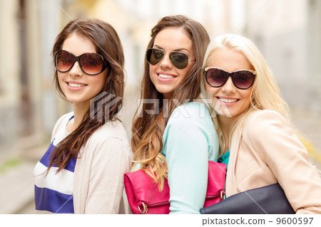 three smiling women in sunglasses with bags 9600597