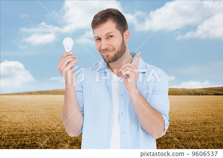 Composite image of charming model holding a bulb in right hand 9606537