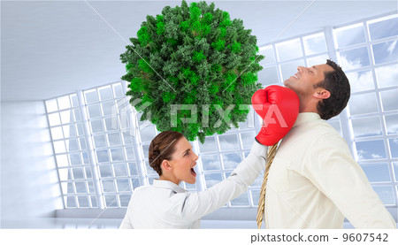 Composite image of businesswoman hitting a businessman with boxi 9607542