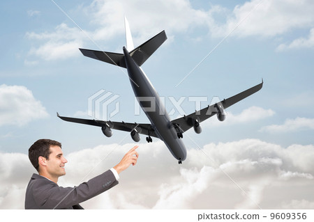 Composite image of smiling classy businessman sitting and pointi 9609356
