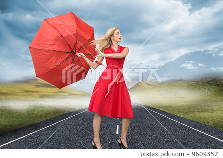 Composite image of beautiful woman posing with a broken umbrella 9609357