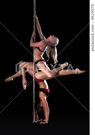 Two graceful young dancers posing on pylon 9629979
