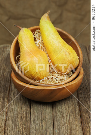 Ripe pears in bowl on wooden background. 9633234