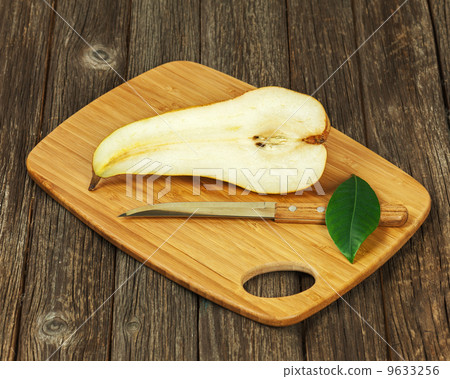 Half of pear and knife on wooden background. 9633256