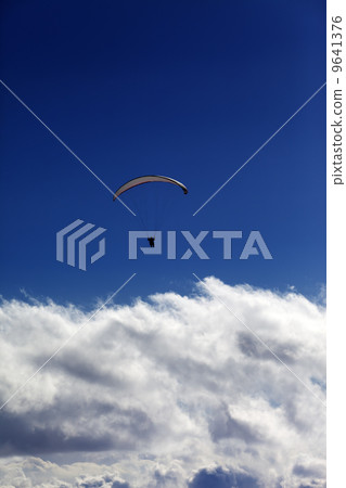 Silhouette of paraglider and blue sky with clouds Silhouette of paraglider and blue sky with clouds 9641376