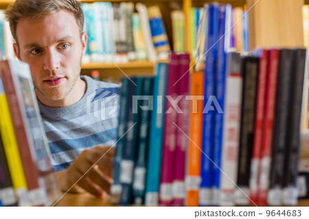 Male student selecting book in the library Male student selecting book in the library 9644683