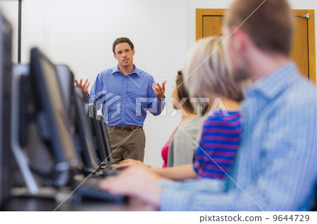 Teacher explaining to students in computer room 9644729