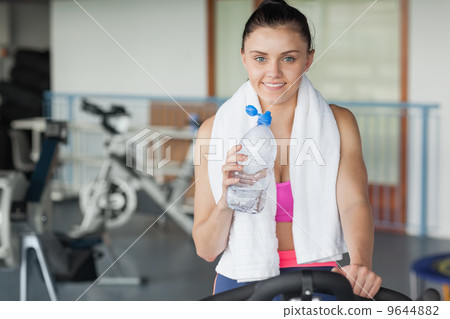 Tired woman drinking water while working out at spinning class Tired woman drinking water while working out at spinning class 9644882