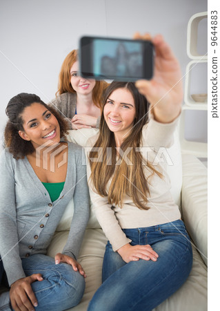 Happy friends photographing themselves with smartphone Happy friends photographing themselves with smartphone 9644883