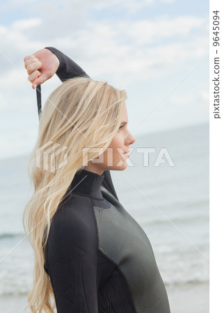 Side view of a blond in wet suit standing at beach 9645094