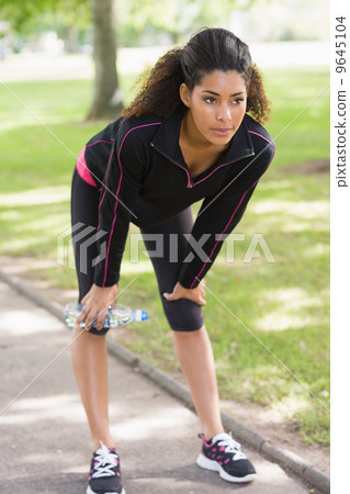Tired healthy woman standing on pathway in the park 9645104