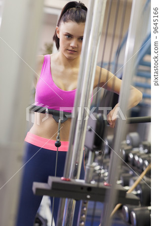 Determined woman doing exercises in gym on lat machine 9645166
