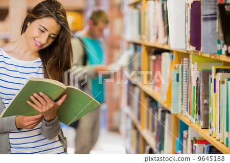 Two young students by bookshelf in the library 9645188