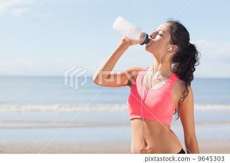 Beautiful healthy woman drinking water on beach Beautiful healthy woman drinking water on beach 9645303