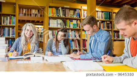 Group of students writing notes at library desk Group of students writing notes at library desk 9645380