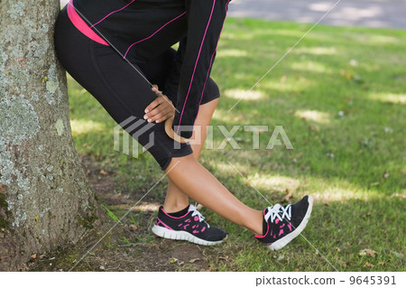 Low section of woman stretching her leg during exercise at park Low section of woman stretching her leg during exercise at park 9645391