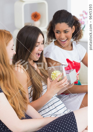 Cheerful young women surprising friend with a gift Cheerful young women surprising friend with a gift 9645393