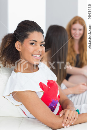 Portrait of a woman with young female friends chatting on sofa Portrait of a woman with young female friends chatting on sofa 9645486