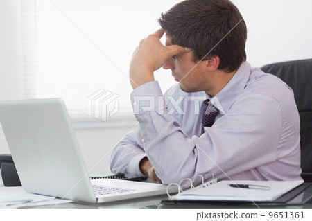 Worried businessman with laptop sitting in office 9651361